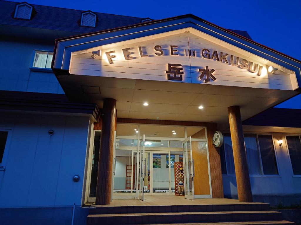 a building with a sign for a restaurant at Felse Inn Gakusui in Hakuba