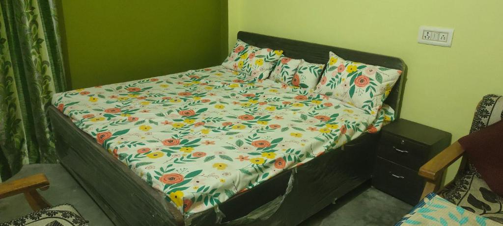 a bed with a floral comforter and pillows at Ayodhya home stay in Faizābād