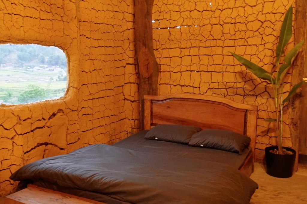 um quarto com uma cama numa parede de pedra em Mơ Niê Farmstay & Cafe em Kon Von Kla