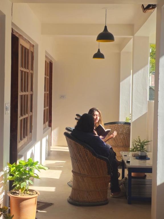 a woman sitting in chairs on a porch at Drifters Inn - The Hidden Tribe in Manāli
