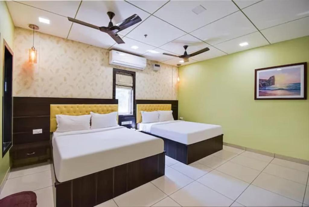 1 dormitorio con 2 camas y ventilador de techo en Goroomgo Royal Crown Puri, en Puri