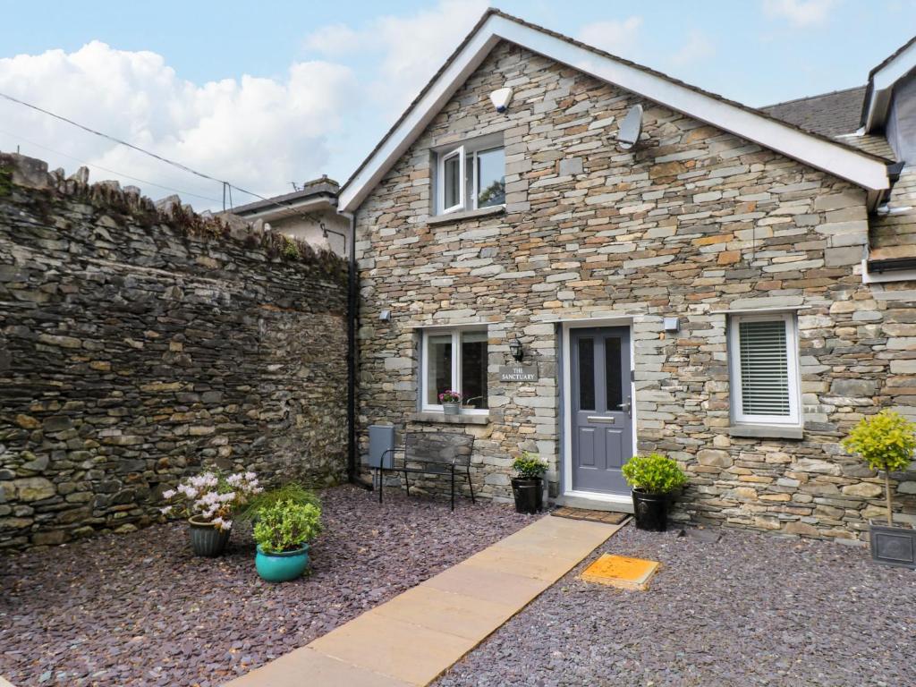 a stone house with a stone wall and a patio at The Sanctuary in Windermere