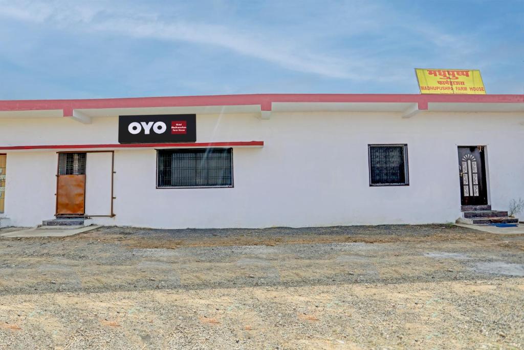 ein weißes Gebäude mit einem qo-Schild drauf in der Unterkunft OYO Madhupushpa Farm House in Rāmtek