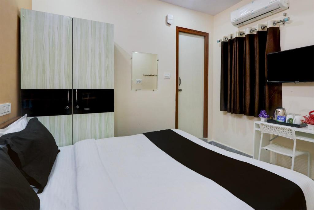 um quarto com uma cama branca e uma secretária em Super Collection O Sri Balaji Luxury rooms em Hyderabad