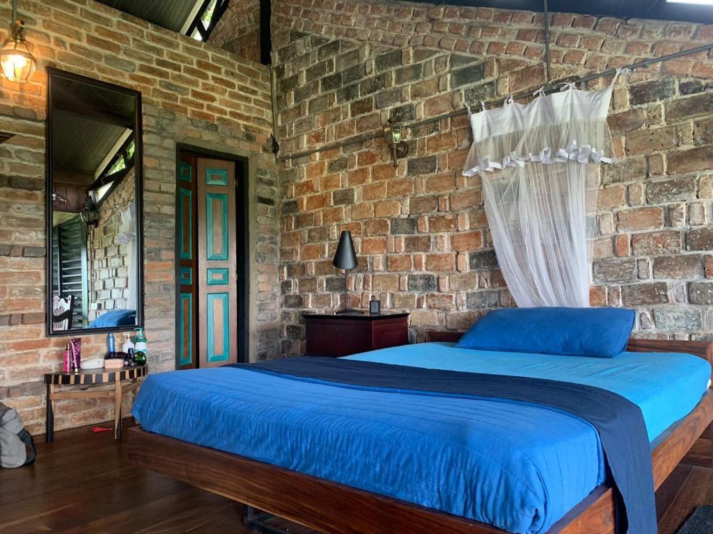 1 dormitorio con 1 cama azul en una pared de ladrillo en TRANQUIL Tropical Hideaway en Kaduwela