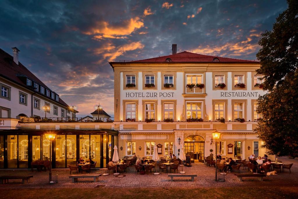 a hotel with people sitting in front of a building at Hotel Zur Post Altötting in Altötting