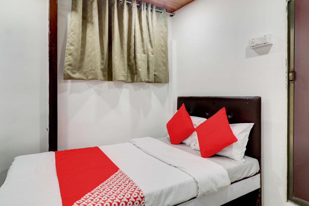 a bedroom with a bed with red and white pillows at Hotel Memsaab Family Residency in Mumbai