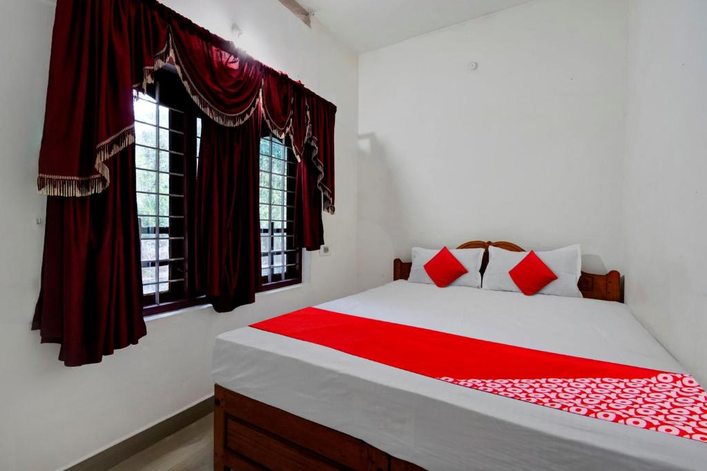 1 dormitorio con 1 cama con sábanas rojas y ventanas en OYO JK Homes, en Pooppara