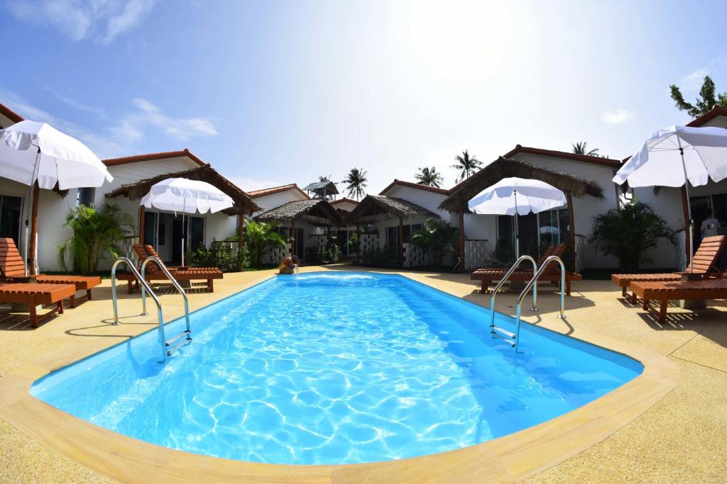 una piscina en un complejo con sillas y sombrillas en Vivi Bungalows Resort, en Nai Harn Beach