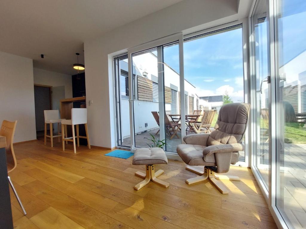 a living room with two chairs and sliding glass doors at Apartmán Business Comfort se zahradou in Hradec Králové