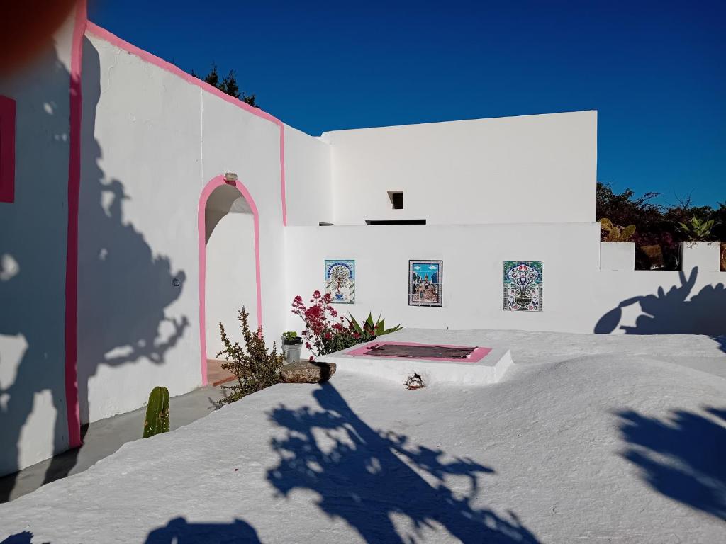 un bâtiment blanc avec une ombre sur son côté dans l'établissement dammusi, à Pantelleria