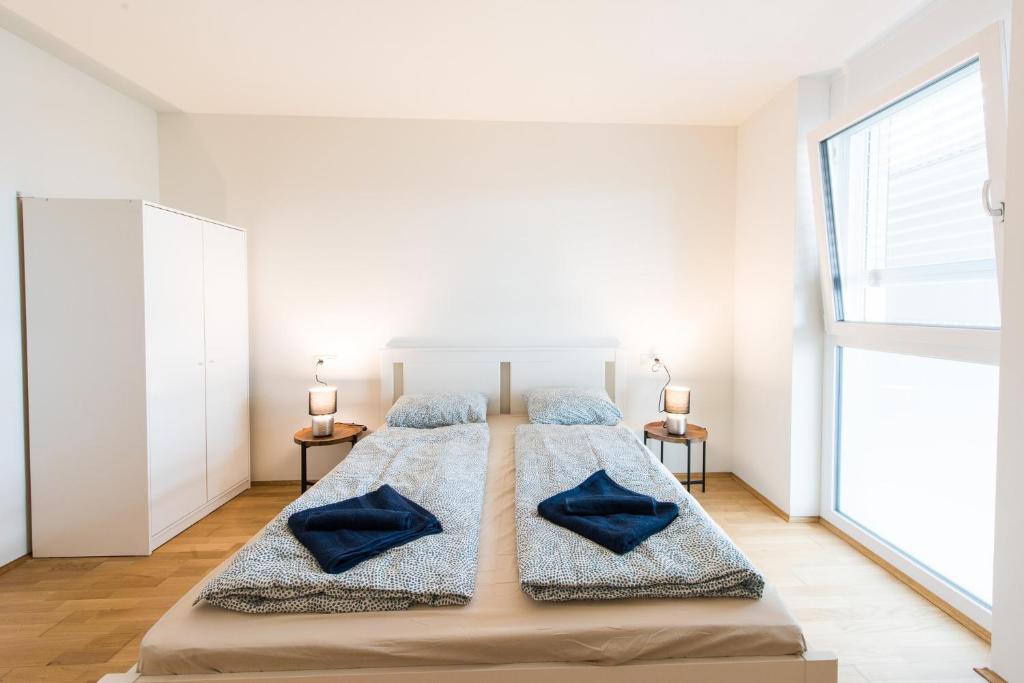 um quarto branco com uma cama grande e almofadas azuis em Muzeta Graz - Eco-Friendly Parkview Holiday Apartments in Graz’s Smart City em Graz