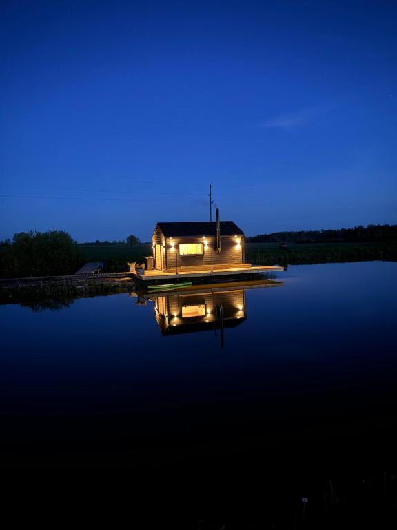 a house on a dock on a lake at night at Glempings lāčuks 