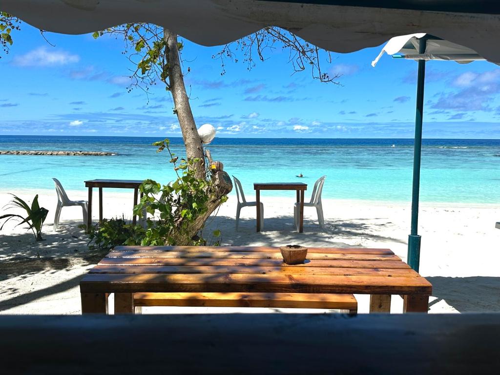 einen Tisch und Stühle am Strand mit Meerblick in der Unterkunft Bougainvillea Inn - Maldives in Fulidhoo