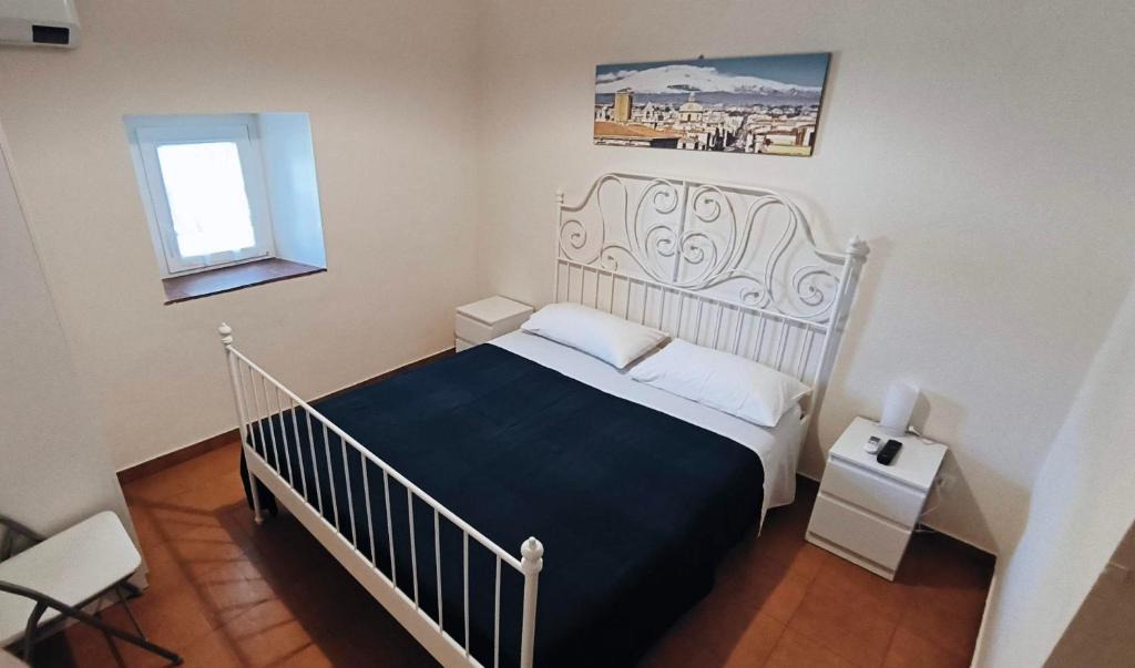 1 dormitorio con cama blanca y manta azul en Villa Egle Belpasso, villa vacanza con piscina, en Belpasso
