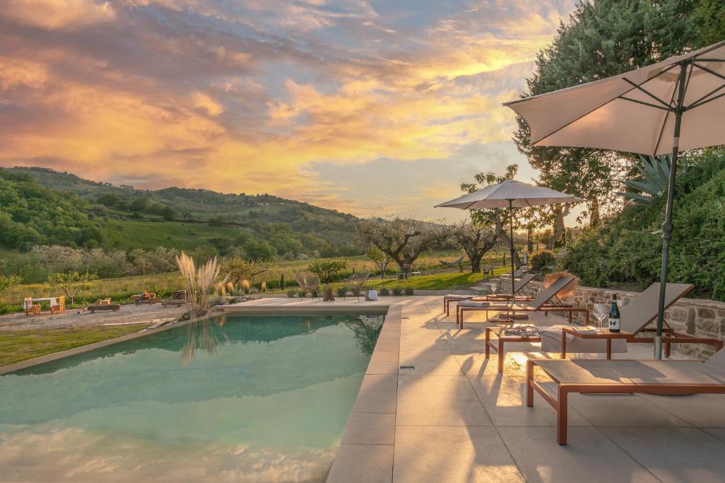 a pool with tables and chairs and an umbrella at B&B Panfilo Farmhouse in Cellino Attanasio