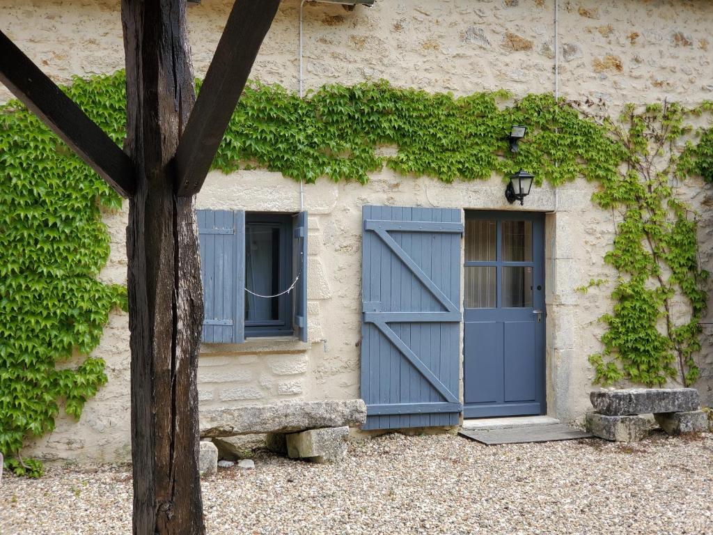 un bâtiment avec une porte bleue et deux fenêtres dans l'établissement LES CHAMBRES DE MIMI, à Vigoux
