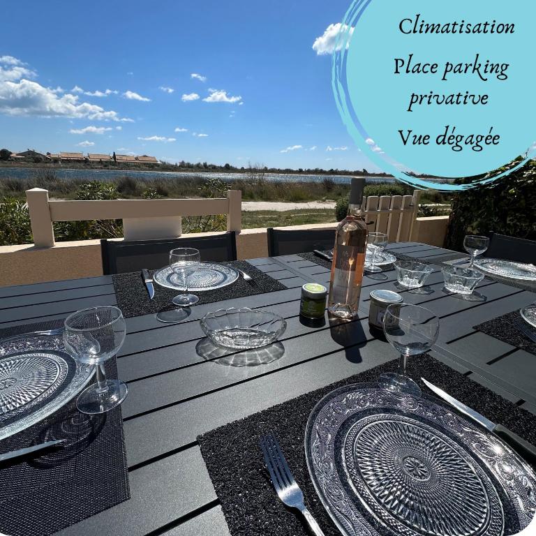 une table en bois avec des assiettes et des verres à vin dessus dans l'établissement Le lagon vue dégagée, à Gruissan