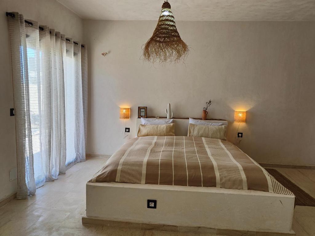 Villa Nour Kélibia في قليبية: غرفة نوم بسرير كبير في غرفة بها نوافذ