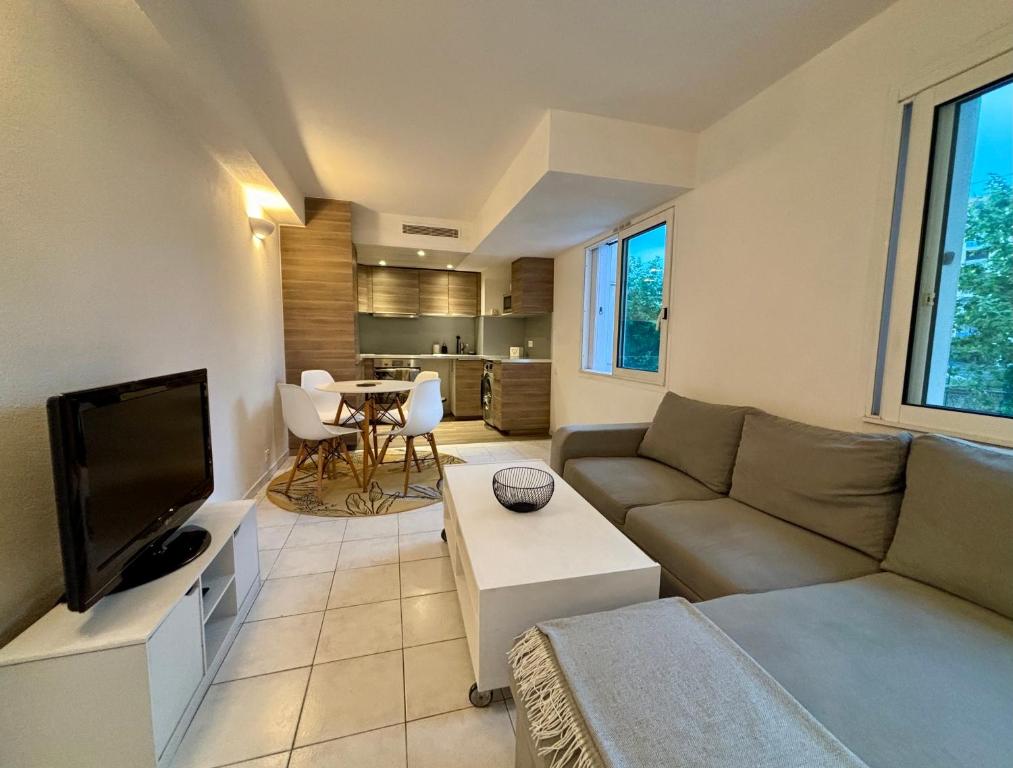ein Wohnzimmer mit einem Sofa und einem TV in der Unterkunft Appartement bord de mer avec piscine in Vallauris