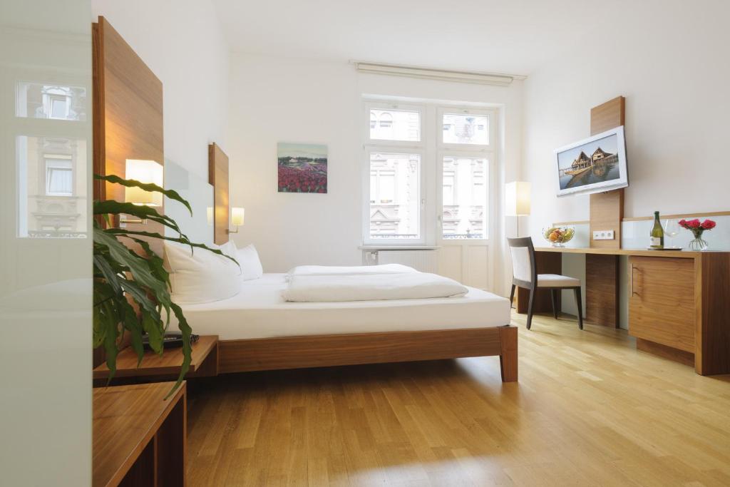 a bedroom with a bed and a desk and a chair at Hotel Augustiner Tor in Konstanz