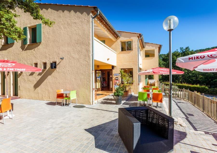 a patio with tables and chairs and umbrellas at Camping aux Vallons in Bauduen