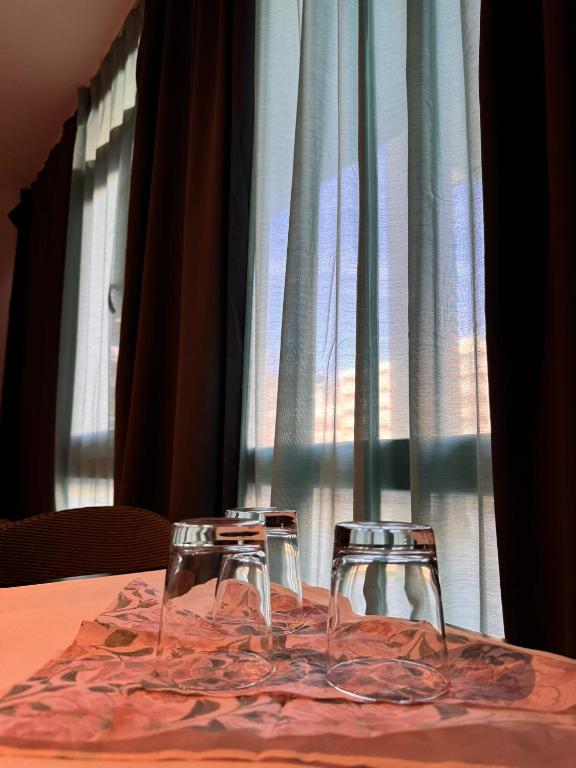 two wine glasses sitting on a table in front of a window at Estelada Hostel Berg am Laim in Munich