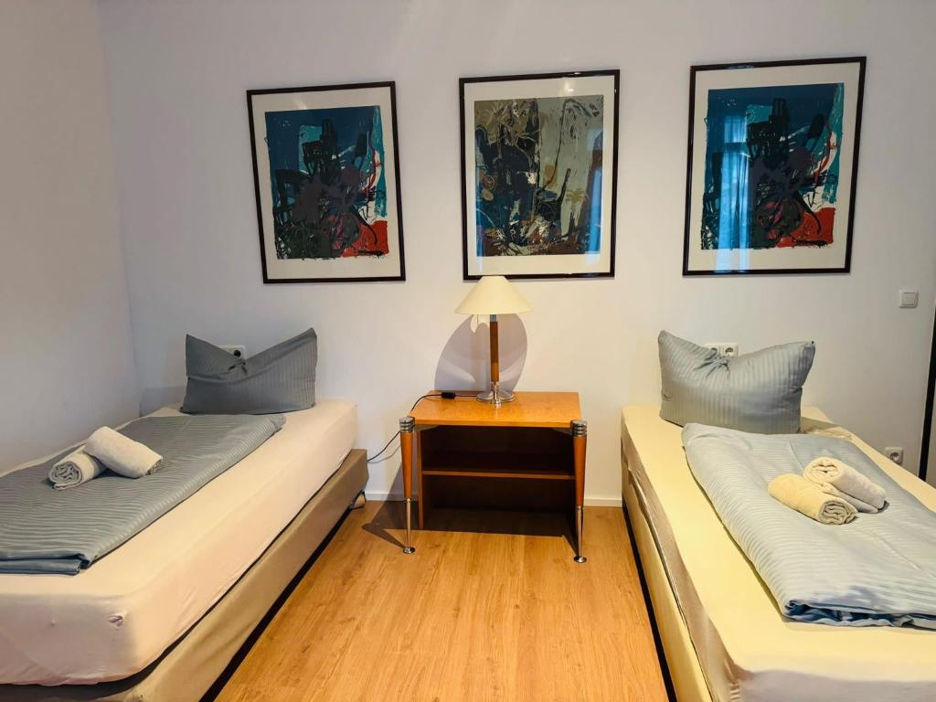 Estelada Boarding Houses في ميونخ: سريرين في غرفة بها لوحات على الحائط