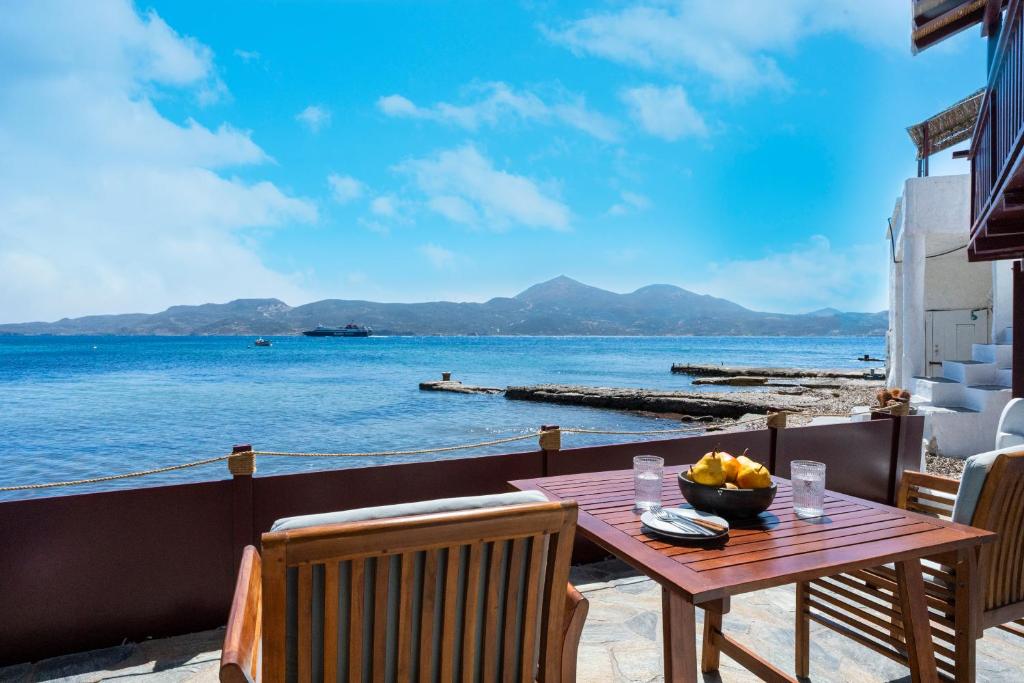 un tavolo di legno con una ciotola di frutta su un balcone con vista sull'acqua di Skinopi Fisherman's Dream a Schinopi