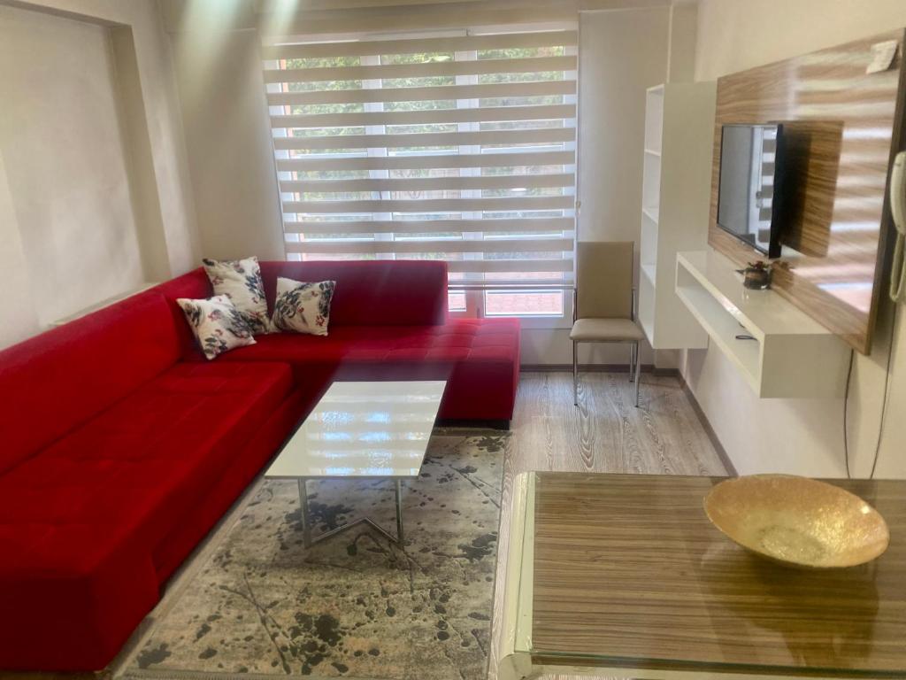 ein rotes Sofa im Wohnzimmer mit TV in der Unterkunft ARGEUS PRESTİJ in Kayseri