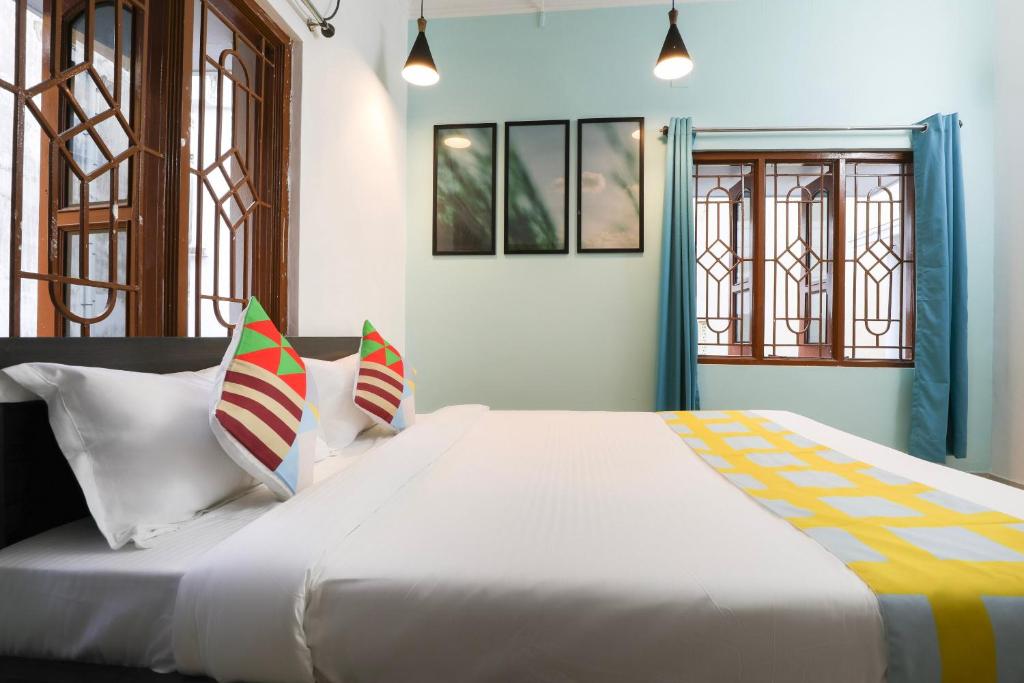 Super OYO JANAPATH INN في Khandagiri: سرير أبيض كبير في غرفة بها نوافذ