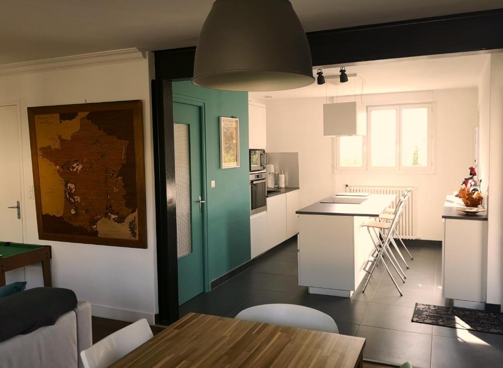 een keuken met een tafel en een groene deur bij Maison et jardin à 5 min de Vannes in Meucon