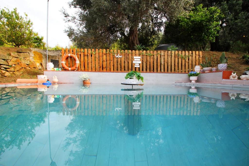 una piscina con algunas plantas y una valla de madera en OASI SICILIANA, en Caronia