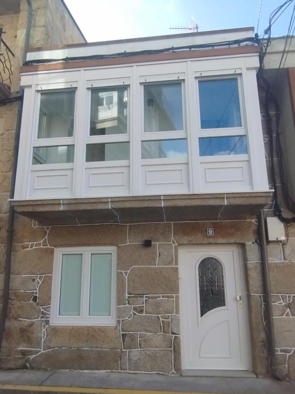 a house with white windows and a door at Casa Anton in Muxia