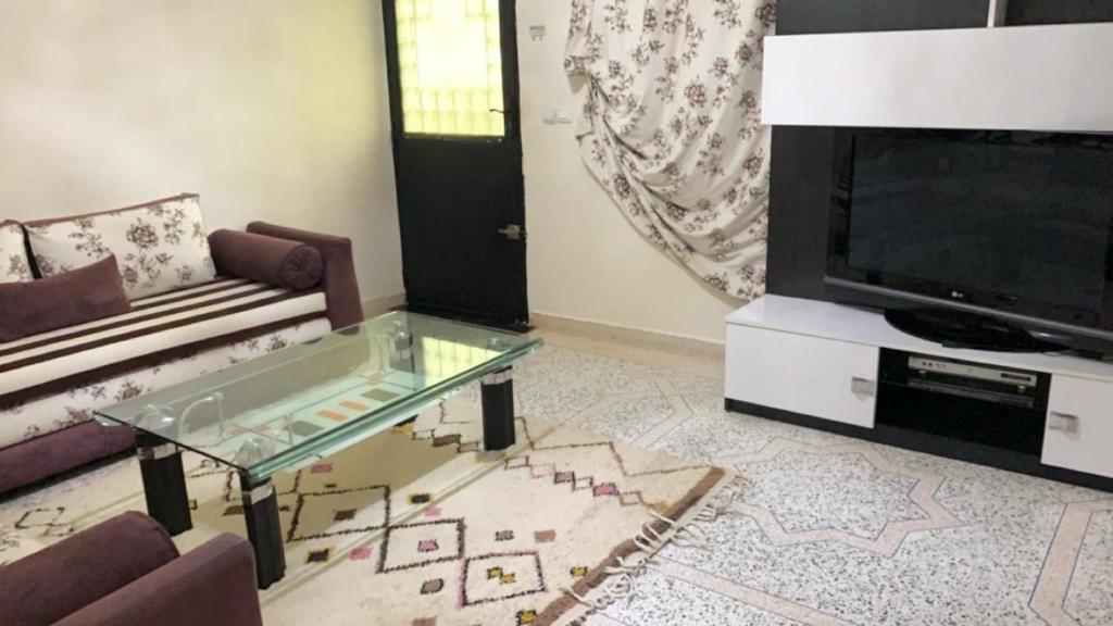 uma sala de estar com uma mesa de café em vidro e uma televisão em 100% famille propre calme plus d’info 06 59 25 27 70 em Fez