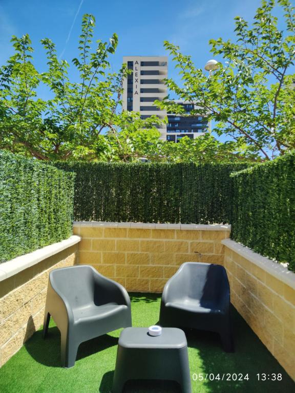 two chairs sitting on the grass in front of a hedge at Apartamentos La Ruta in Calpe