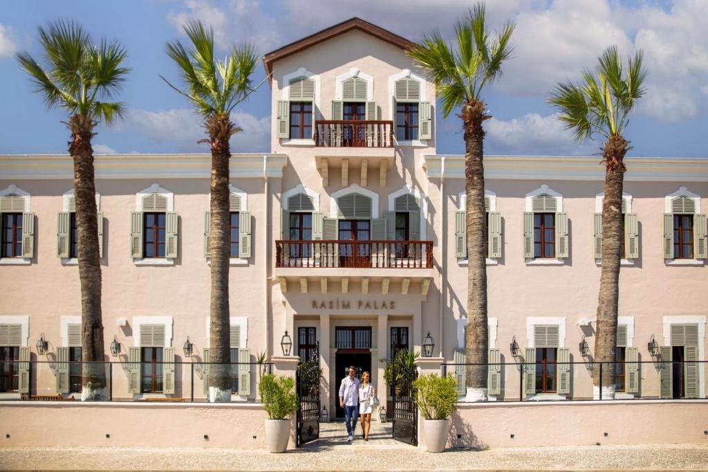a building with palm trees in front of it at Rasim Palas - Adults Only in Cesme