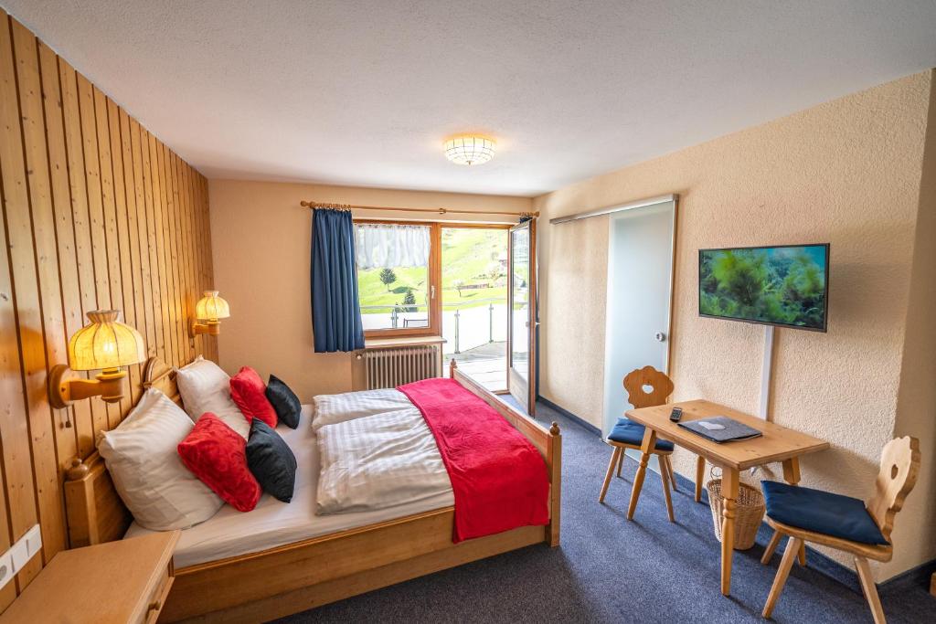 ein Hotelzimmer mit einem Bett, einem Schreibtisch und einem Fenster in der Unterkunft Schwarzwald Hotel Wiedenerhof in Wieden
