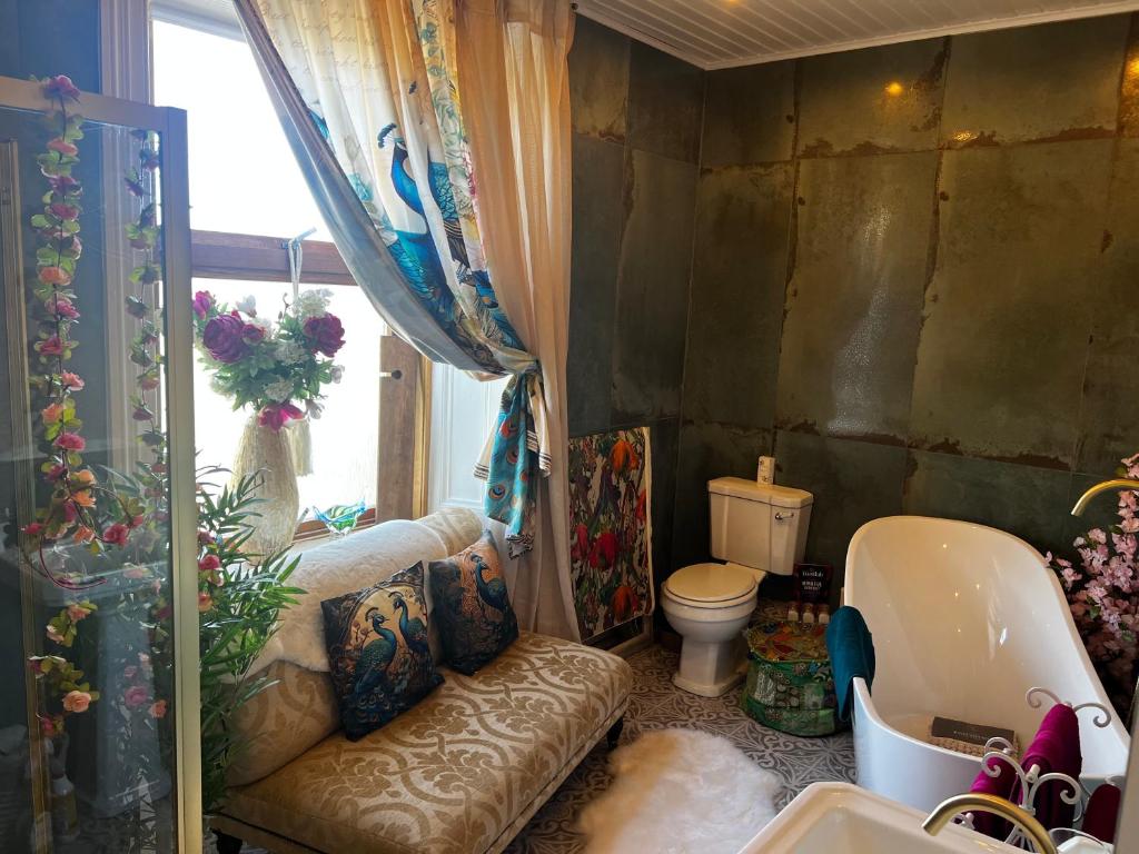 a bathroom with a couch and a toilet in it at Belmont House Boutique - the Kingsley collection in Berwick-Upon-Tweed