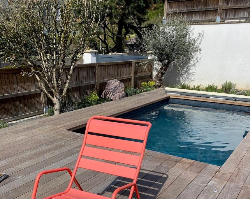 une chaise rouge assise à côté de la piscine dans l'établissement Location maison Versailles piscine -5 chambres, à Versailles