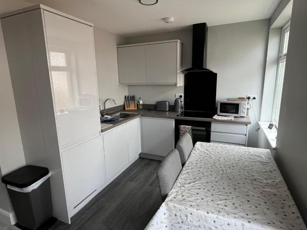 a small kitchen with white cabinets and a table at New 2 bedroom first floor apartment close to beach in Southbourne