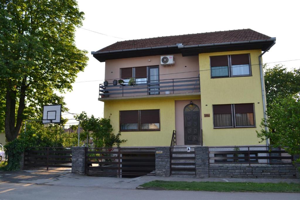 una casa gialla con un balcone sopra di Apartman Gluhović a Sombor
