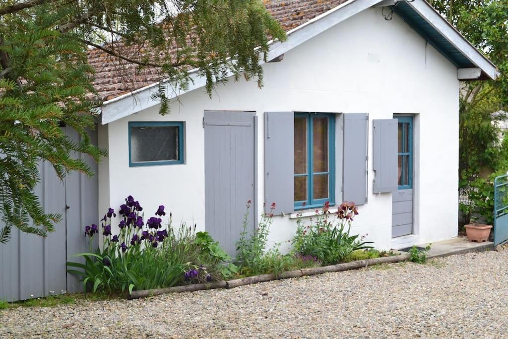 une maison blanche avec des fleurs devant elle dans l'établissement La Maisonnette du Jardin Caché, à Marmande