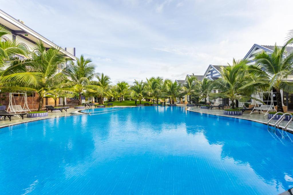 a large blue swimming pool with palm trees at Thuong Trang Villa Phu Quoc in Phu Quoc