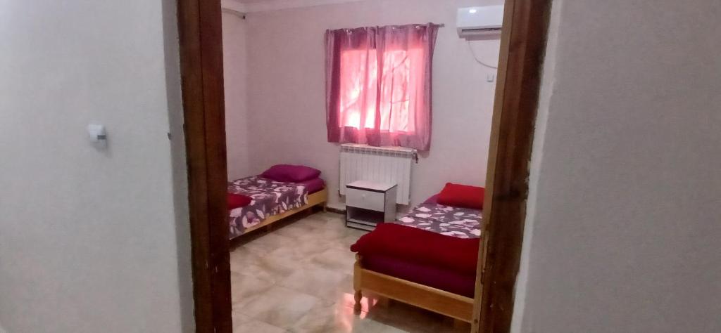 Cette petite chambre comprend 2 lits et une fenêtre. dans l'établissement Hostel 1 er novembre khenchela, à Khenchela
