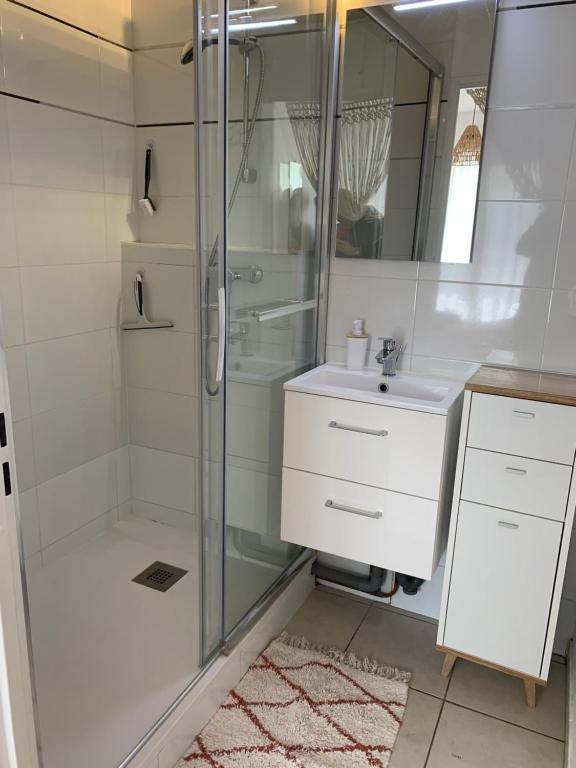 La salle de bains blanche est pourvue d'une douche et d'un lavabo. dans l'établissement Appartement cossy 1 chambre pour 2 pers - rénové - terrasse - parking, à Dinard