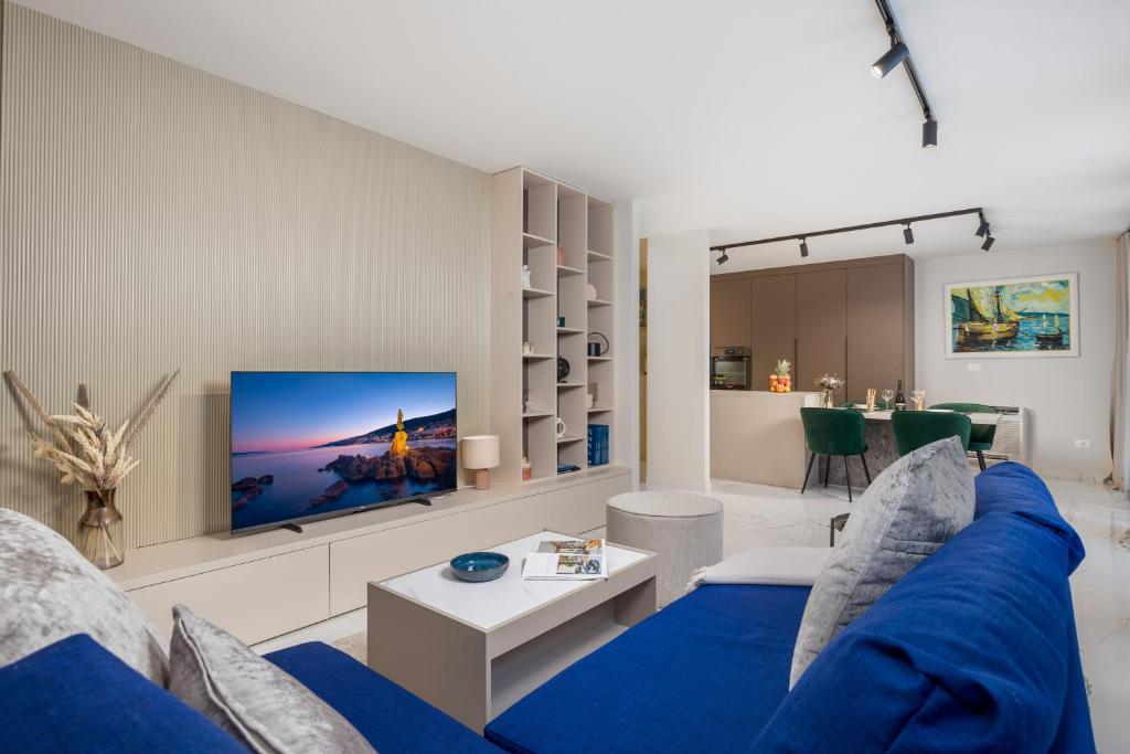 een woonkamer met een blauwe bank en een tv bij Abau Residence Apartment 2 Opatija in Opatija