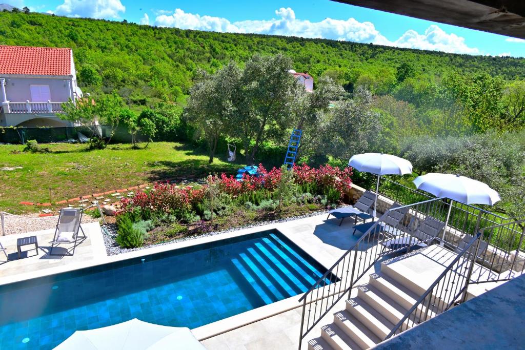 a swimming pool with chairs and umbrellas in a yard at Vacation house Rubi in Dubrovnik