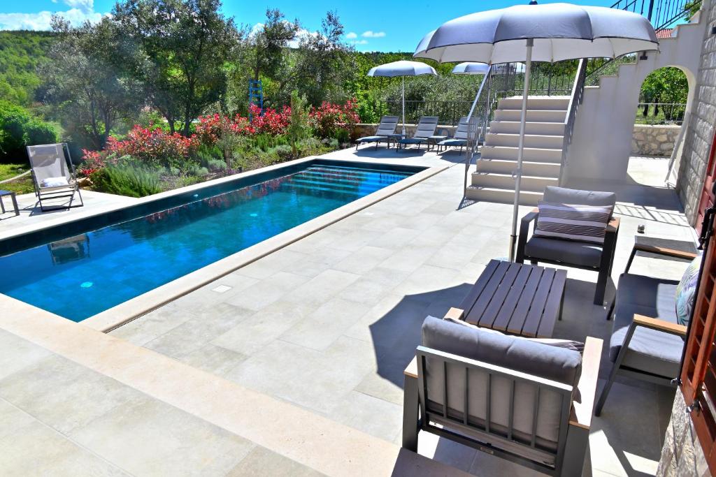 a pool with chairs and an umbrella next to a swimming pool at Vacation house Rubi in Dubrovnik