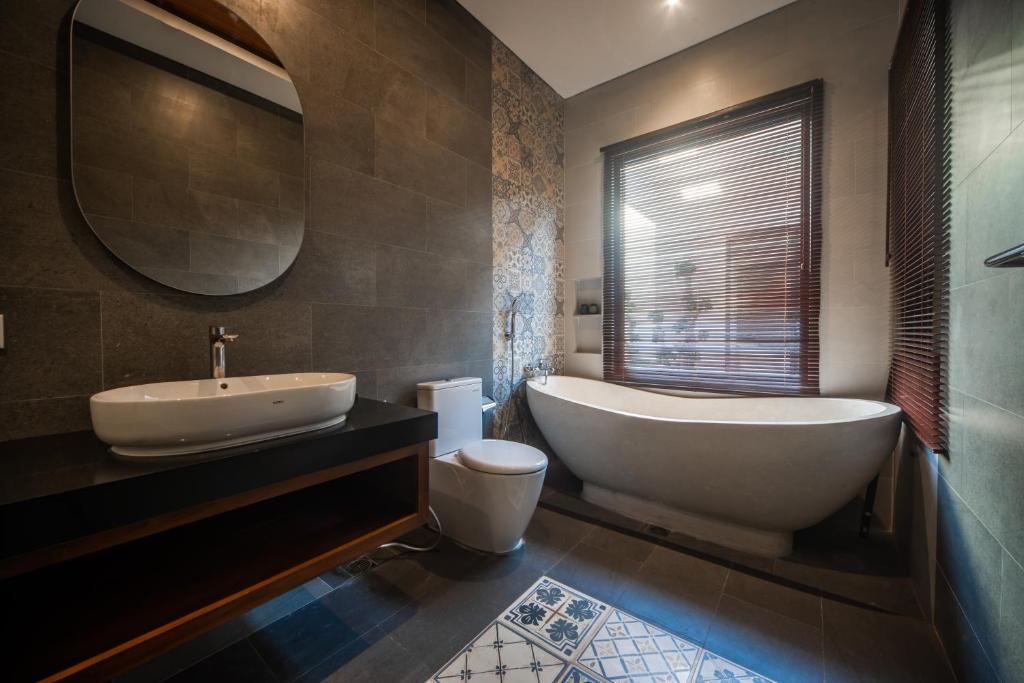 a bathroom with a tub and a sink and a toilet at Gaing Mas Jimbaran Villas by Gaing Mas Group in Jimbaran